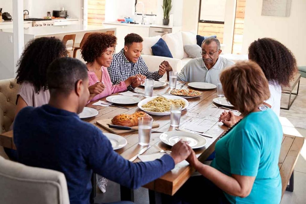 Família orando agradecendo a Deus pela refeição